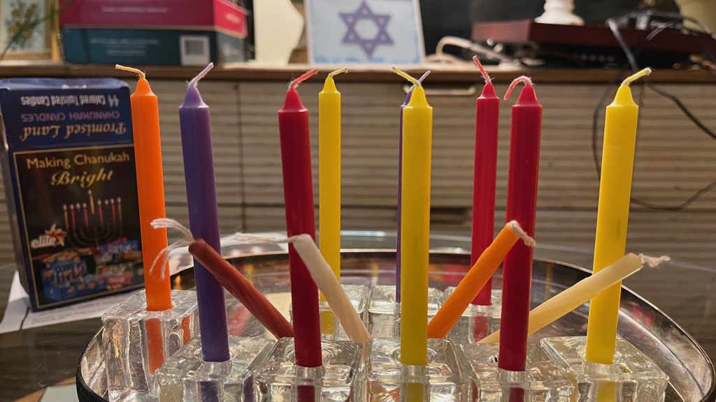 Twelve Hanukkah candles plus the shammash helper candle are arranged on a typical nine-spot menorah.