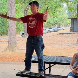 Ben Pollock, president of UA-Fayetteville Educational Association, hails the estimated 6 dozen attending the 2026 Labor Day Labor Picnic, Sept. 7, at Veterans Memorial Park in Fayetteville.