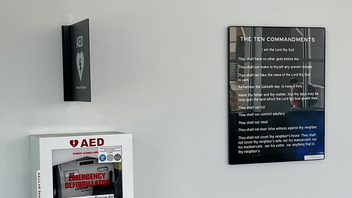 One of the 500 posters of the Ten Commandments donated to the University of Arkansas, mounted at Union Station next to a defibrillator.